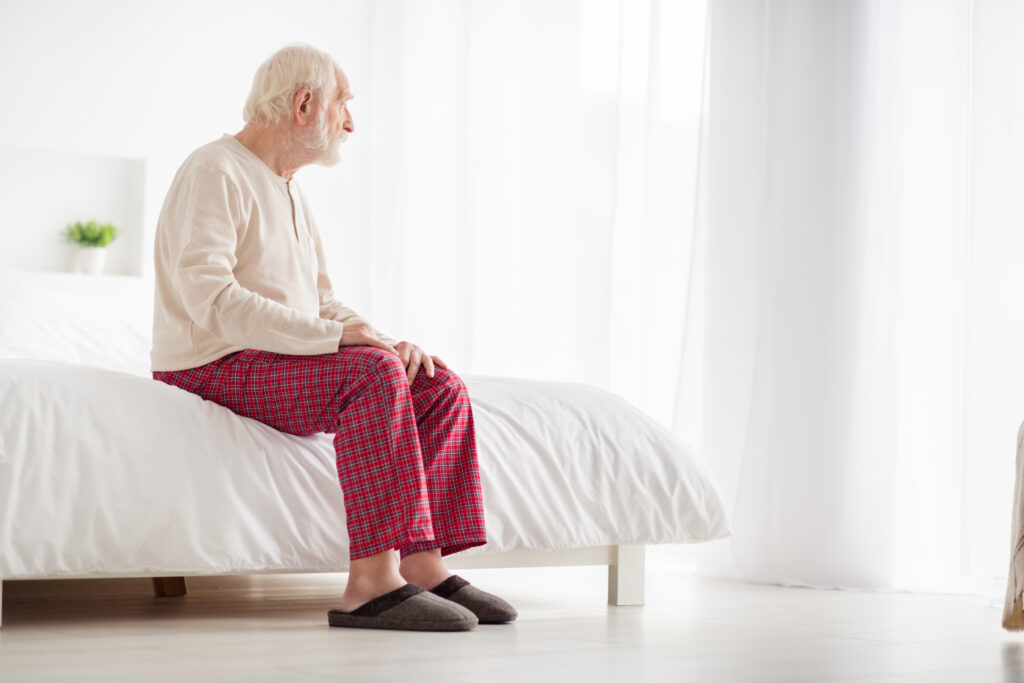 Mann sitzt auf einem Bett